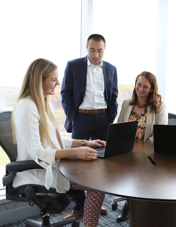 Three First American colleagues smiling at laptop.